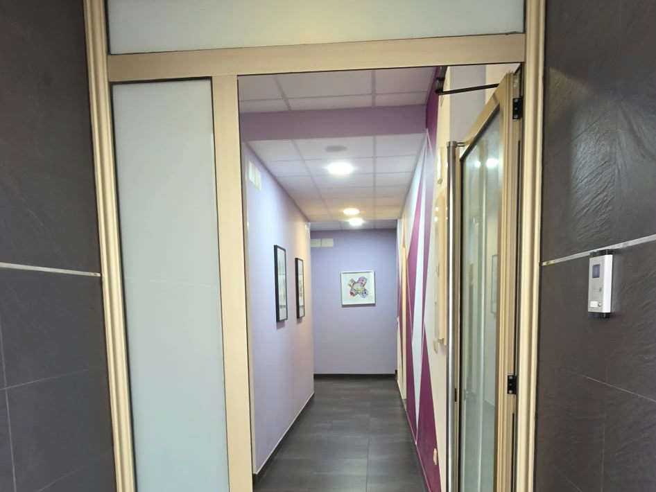 Puerta de entrada de Logoter y pasillo interior de paredes lilas que lleva a las salas