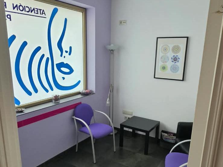 Sala de espera con sillas moradas, lámpara de pie y cuadros