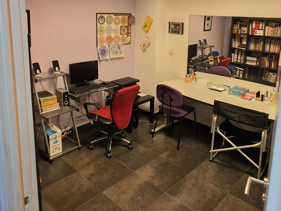Sala de pedagogía con puesto de ordenador, mesa de estudio y estanterías de libros